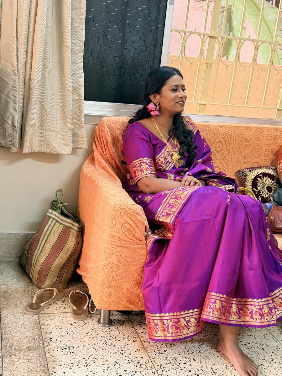 Rituparna sitting gracefully in her purple Banarasi on orange cushions