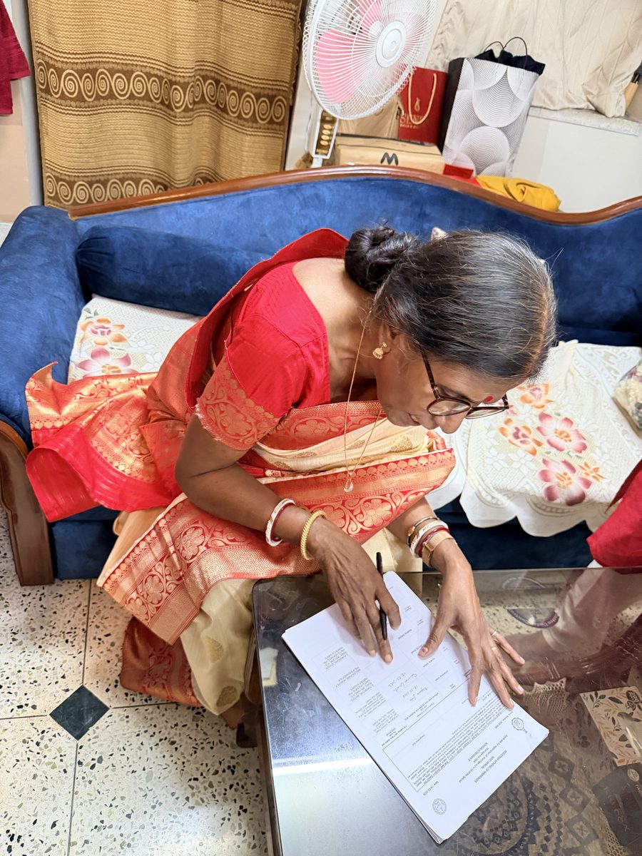 Woman in red sari reviewing and signing ceremony documents