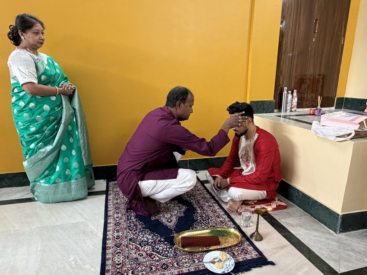 Man in maroon receiving blessings from an elder woman in green