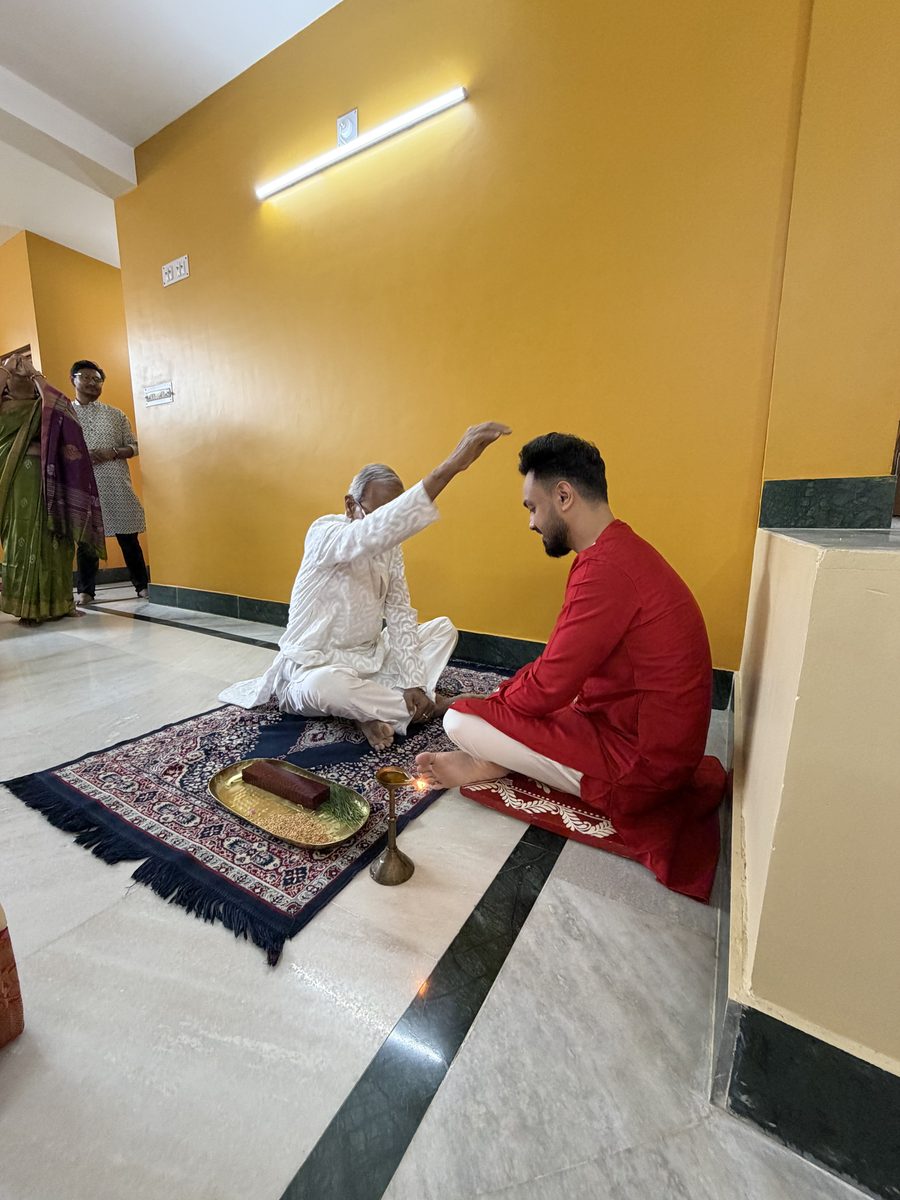 Elder in white giving blessings to Shoumo on the prayer mat