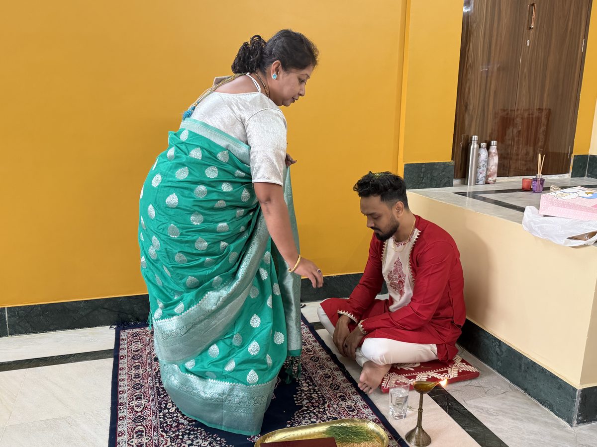 Woman giving blessings to Shoumo seated on the prayer mat