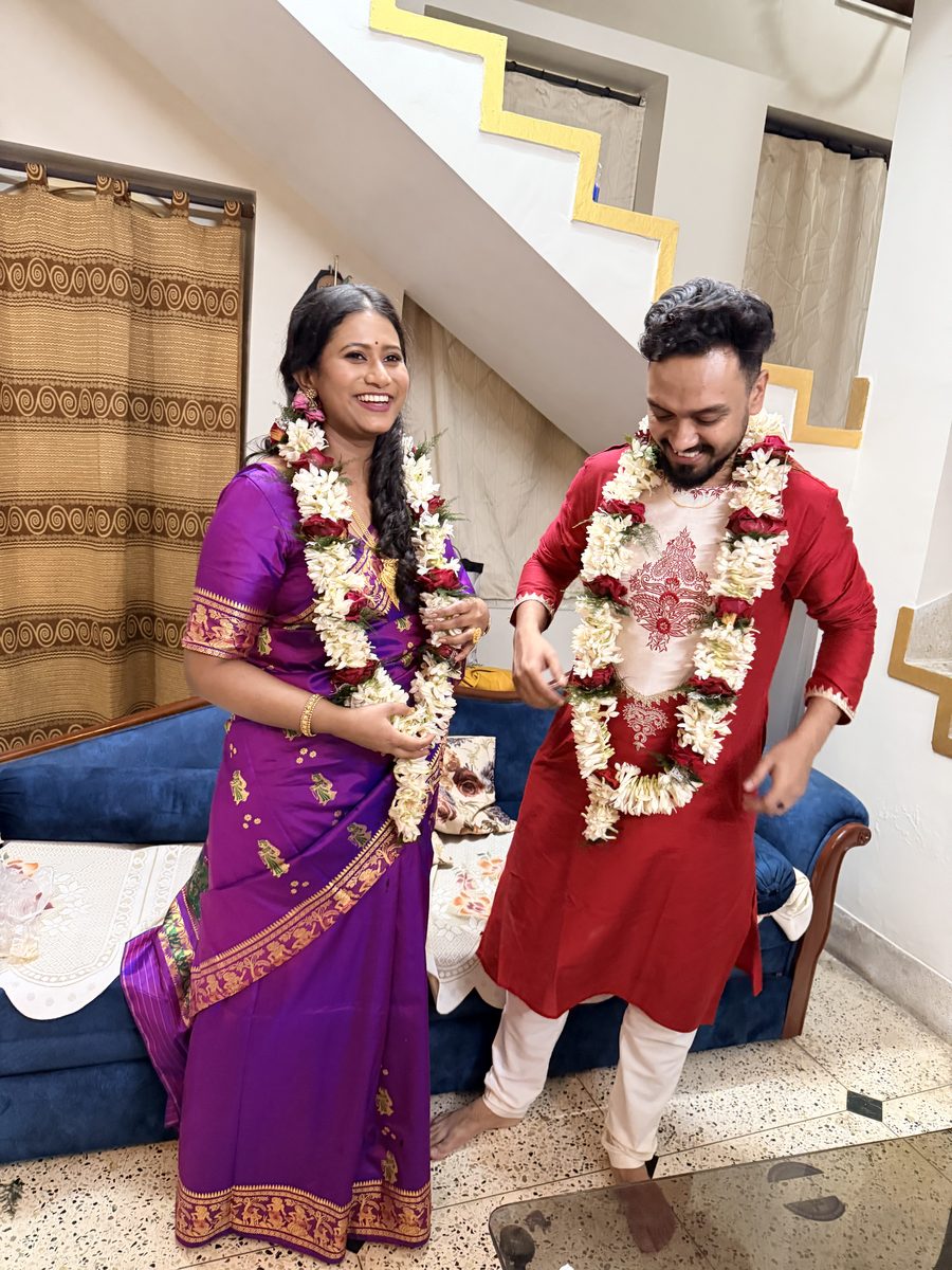 Rituparna and Shoumo with matching flower garlands, smiling directly at camera