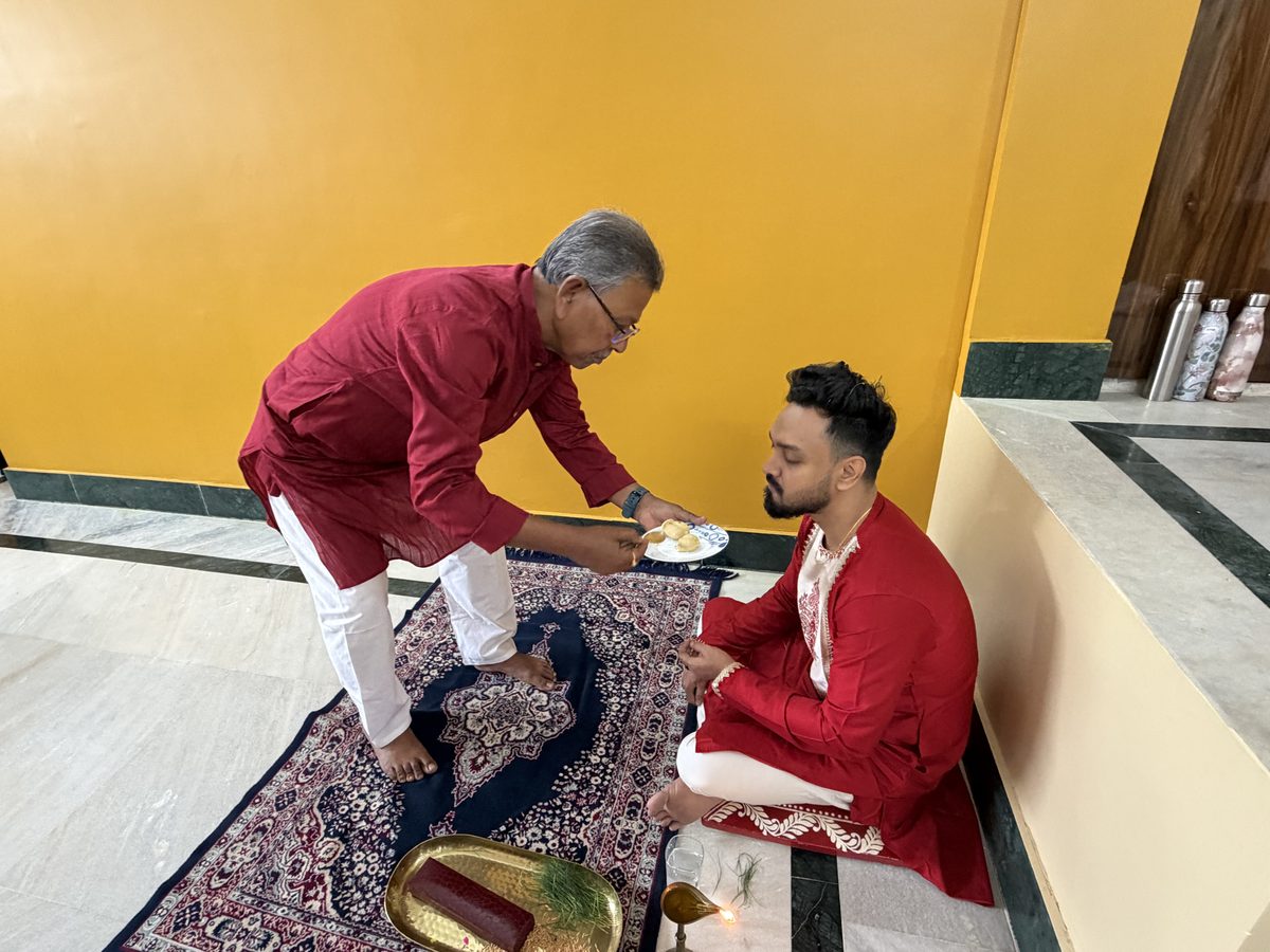 Elder man in maroon blessing Shoumo on the decorative mat